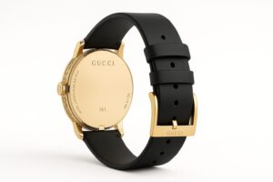 ゴールドの裏蓋に「GUCCI」と「SWISS MADE」の刻印がある高級腕時計。黒のレザーストラップとゴールドバックルが装着されており、白背景でスタジオ撮影された後方アングル。